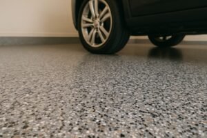 A flake epoxy floor in a Dallas garage from a low perspective with the wheels of a car in the background.